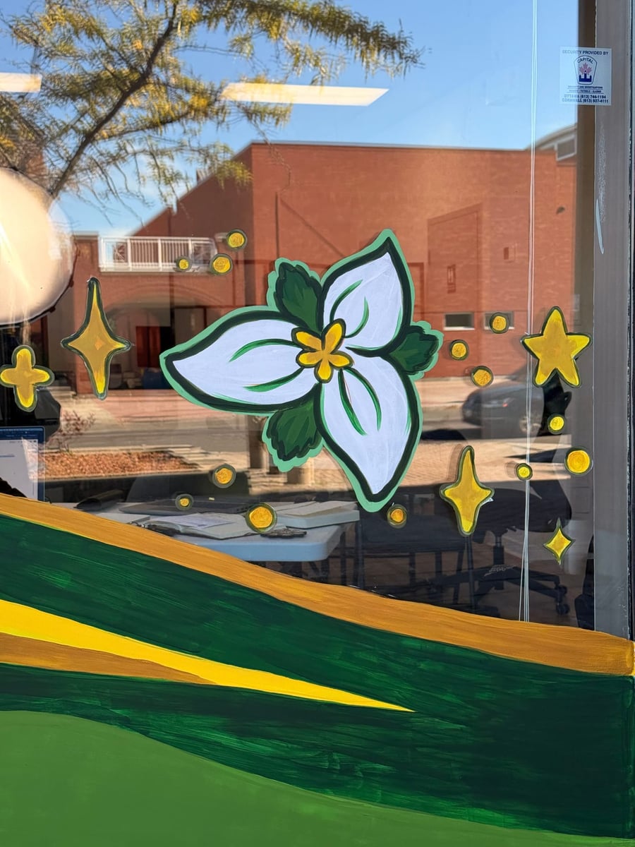 A hand-painted trillium with yellow stars on an Orléans storefront window.